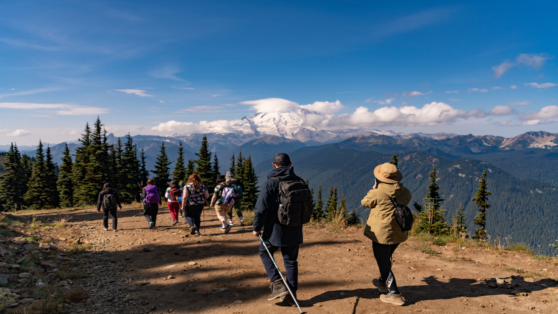 A group of hikers walk a trail at Crystal Mountain with Mount Rainier in the background.