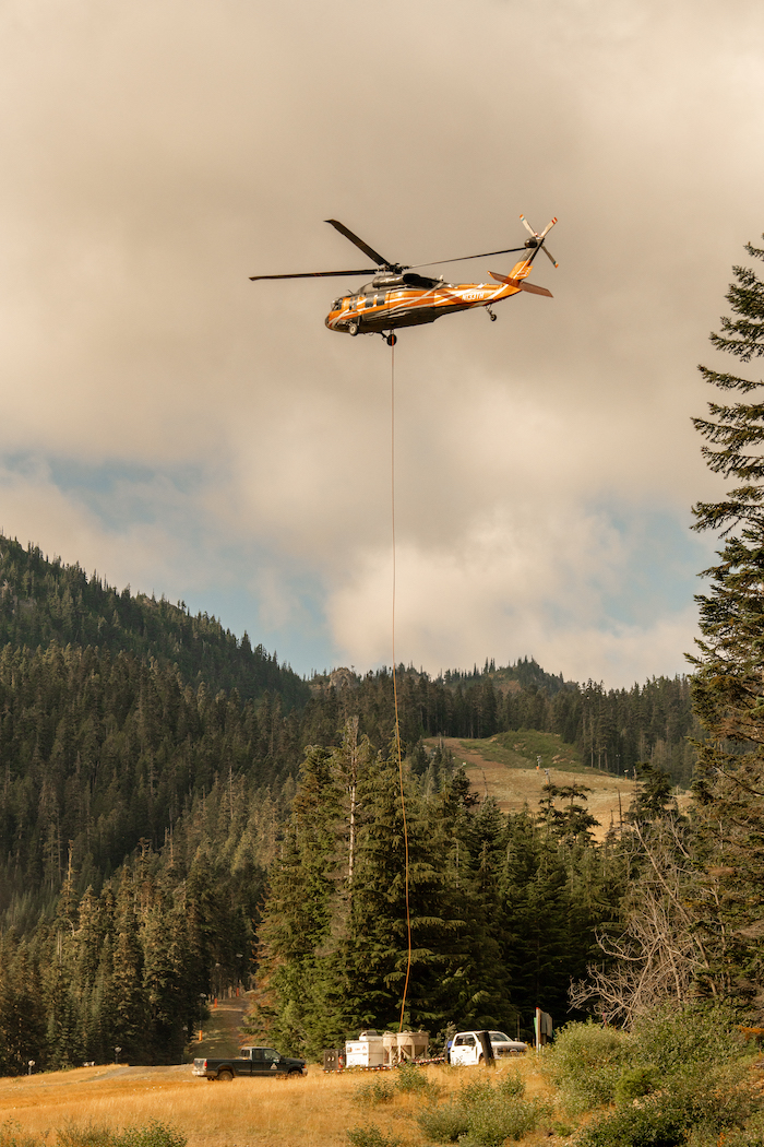 A helicopter hovers above mountain scenery.