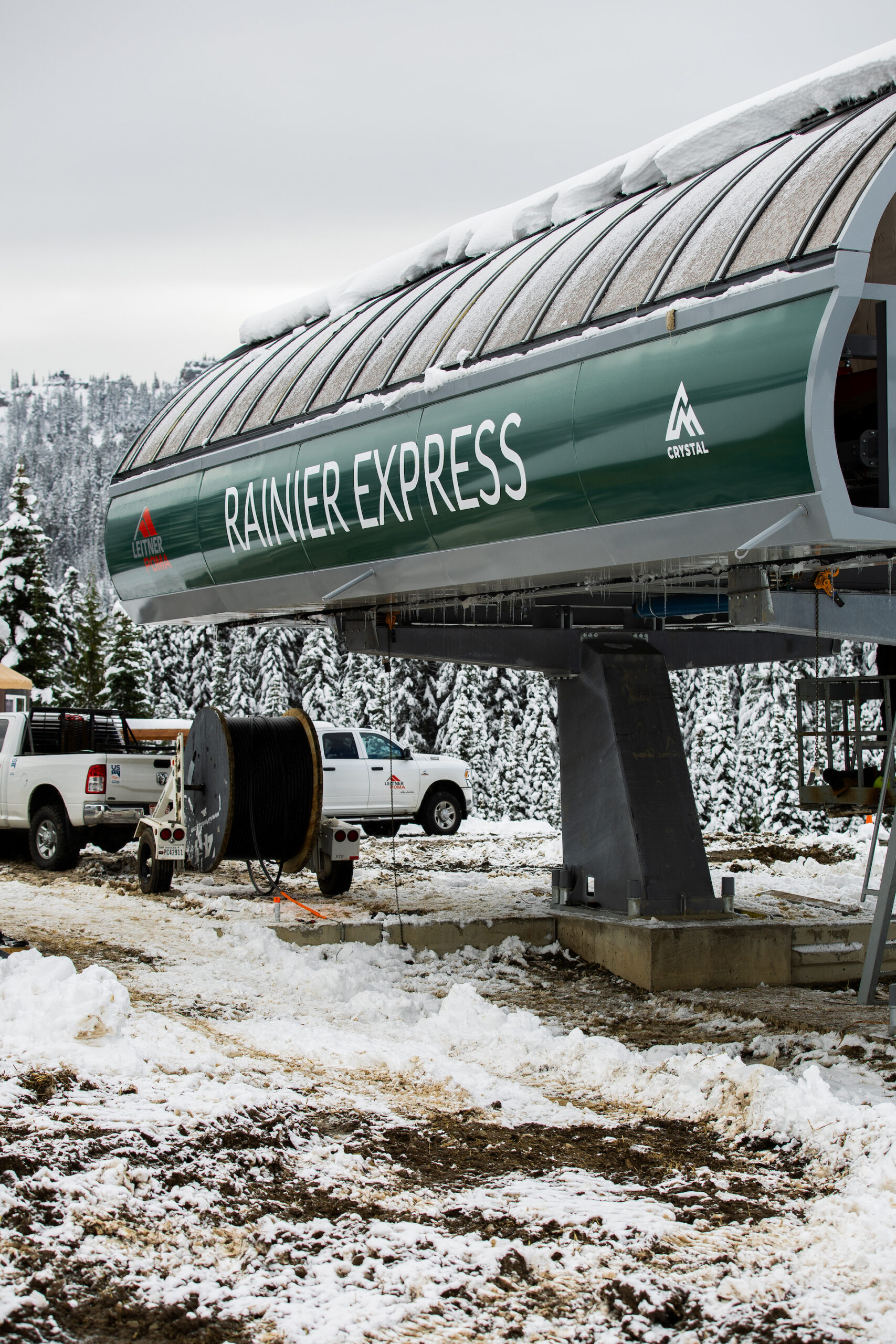 Lift terminal at Ski lift base construction site with snow on the ground and Rainier Express written in green.