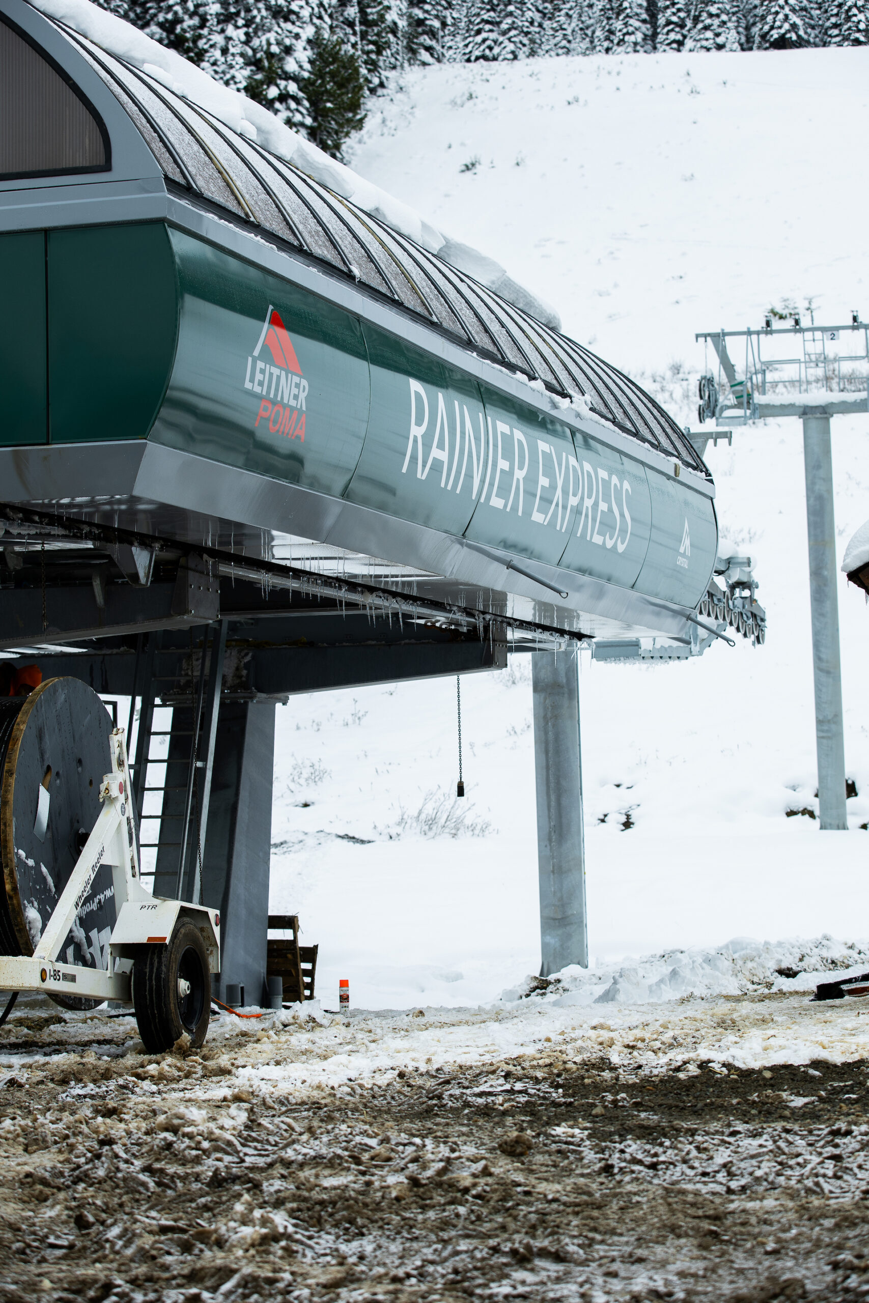 Lift terminal at Ski lift base construction site with snow on the ground and Rainier Express written in green.