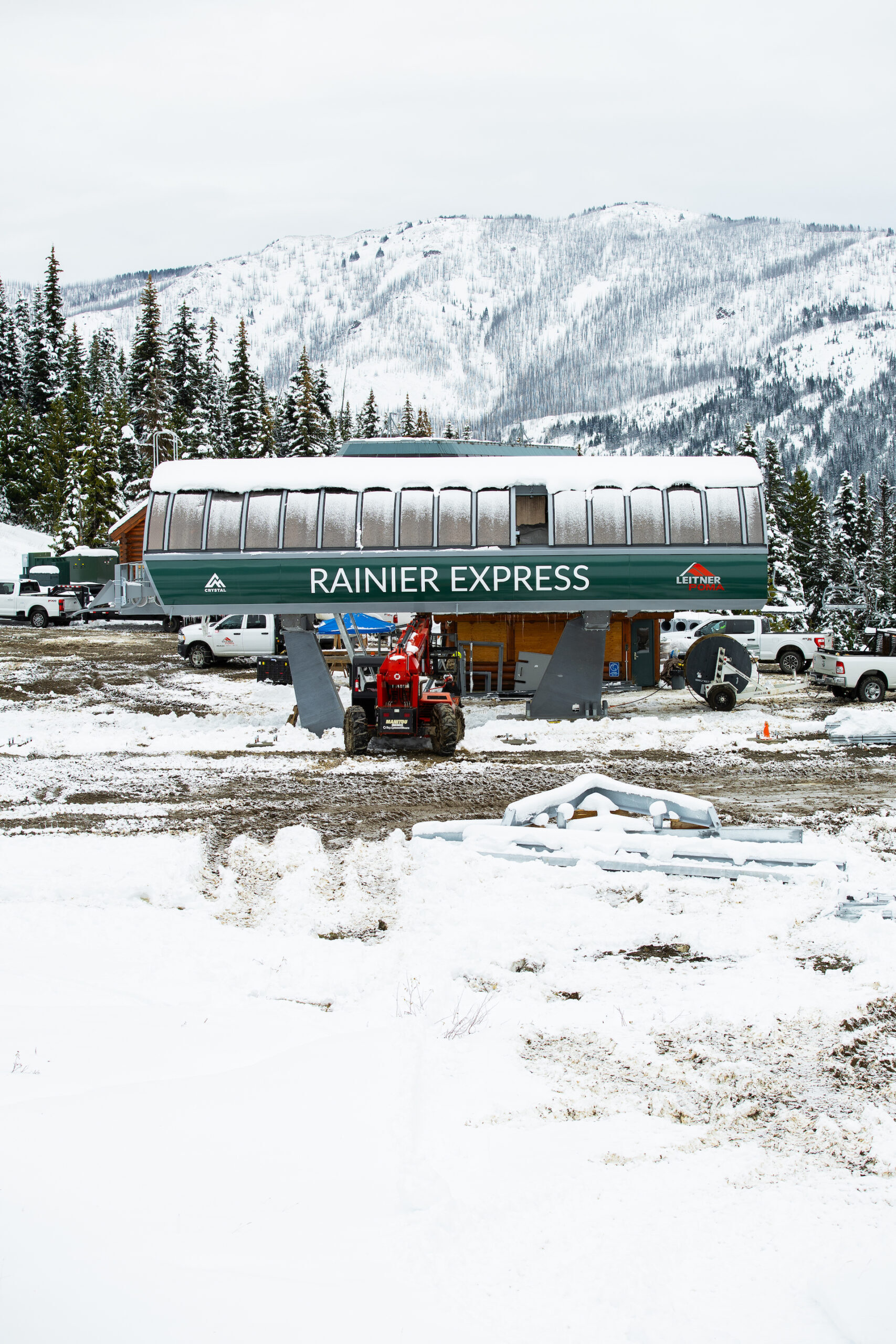 Lift terminal at Ski lift base construction site with snow on the ground and Rainier Express written in green.