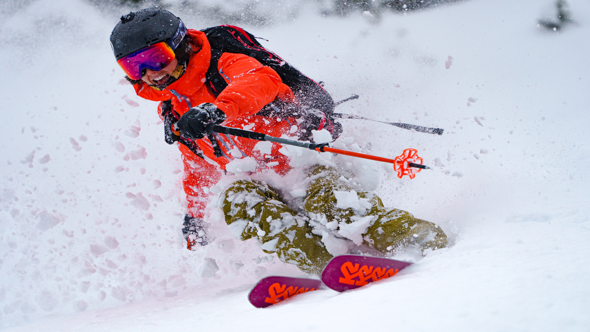 Skier with K2 skis and bright snow clothing creates a powder splash.