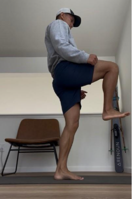 A person lifting their knee up facing a wall
