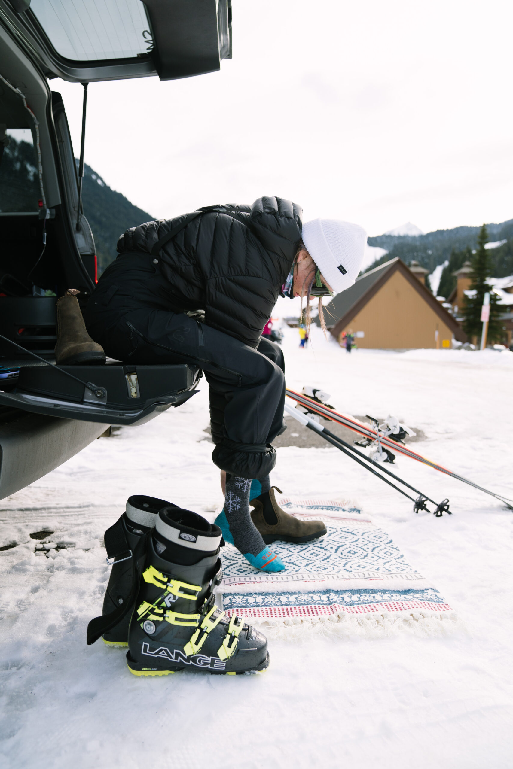 Woman swaps her snow boots for shoes at her car