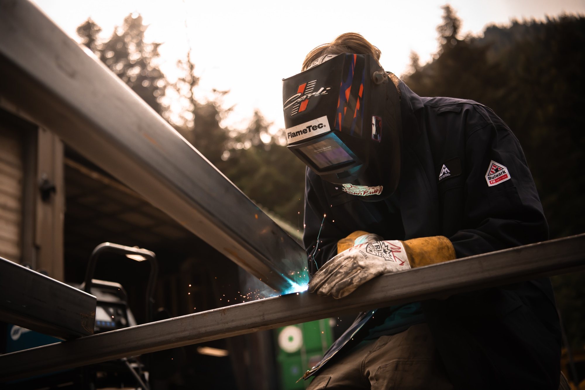 Worker welds with welding mask on.